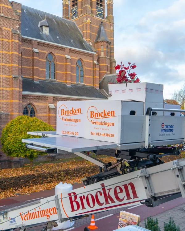 Liftplateau met verhuisdozen van Brocken Verhuizingen boven een kerkplein