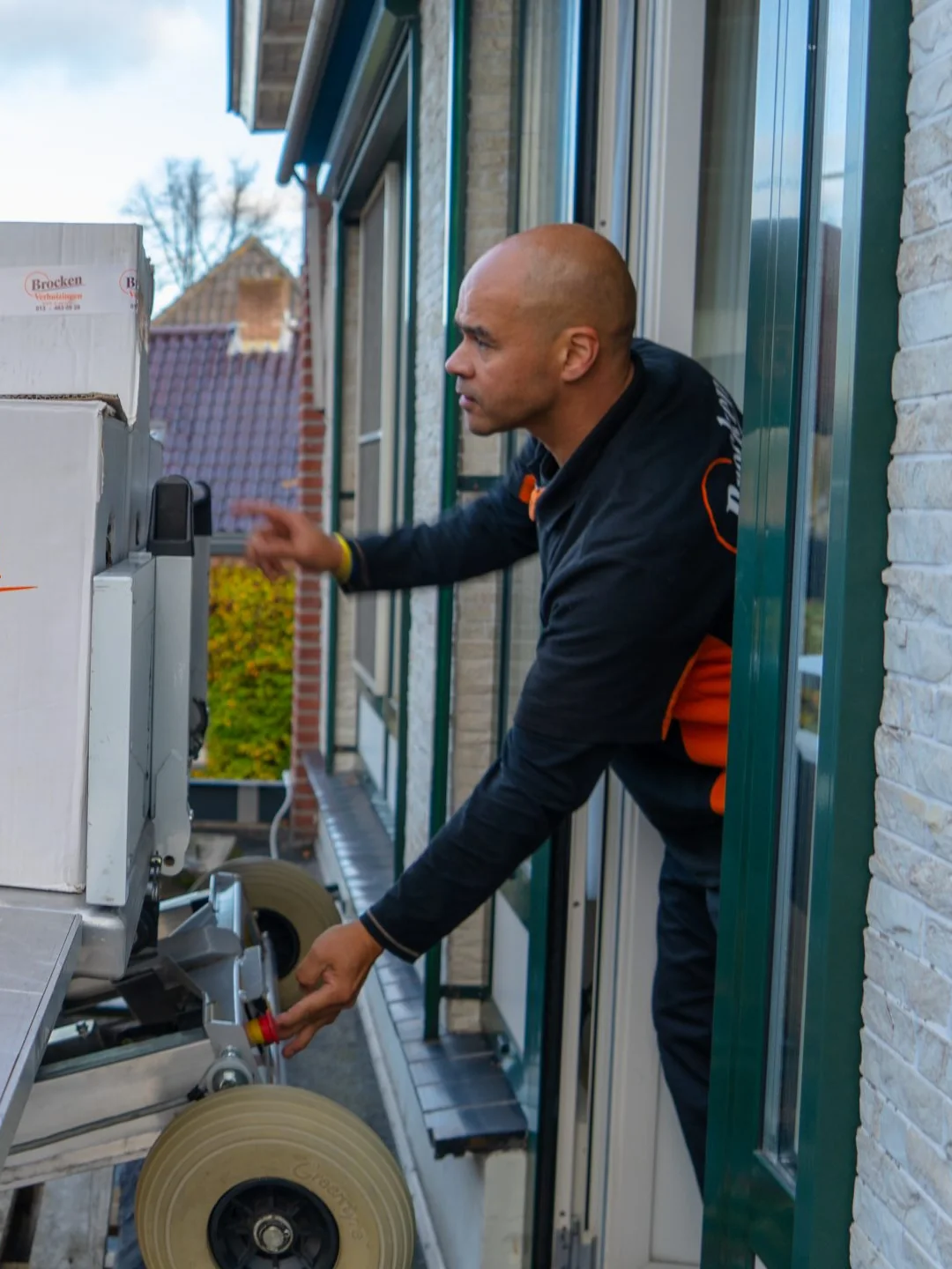 Een verhuizer van Brocken Verhuizingen neemt bij een open raam dozen aan van het plateau van de verhuislift