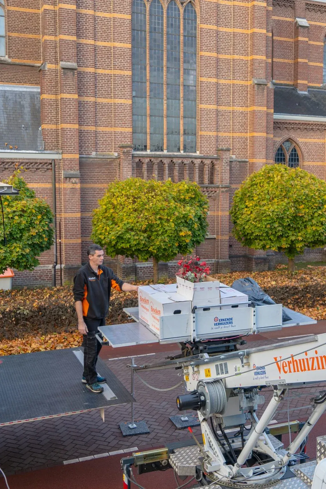 Een verhuizer van Brocken Verhuizingen zet dozen en een plant klaar op het plateau van de verhuislift